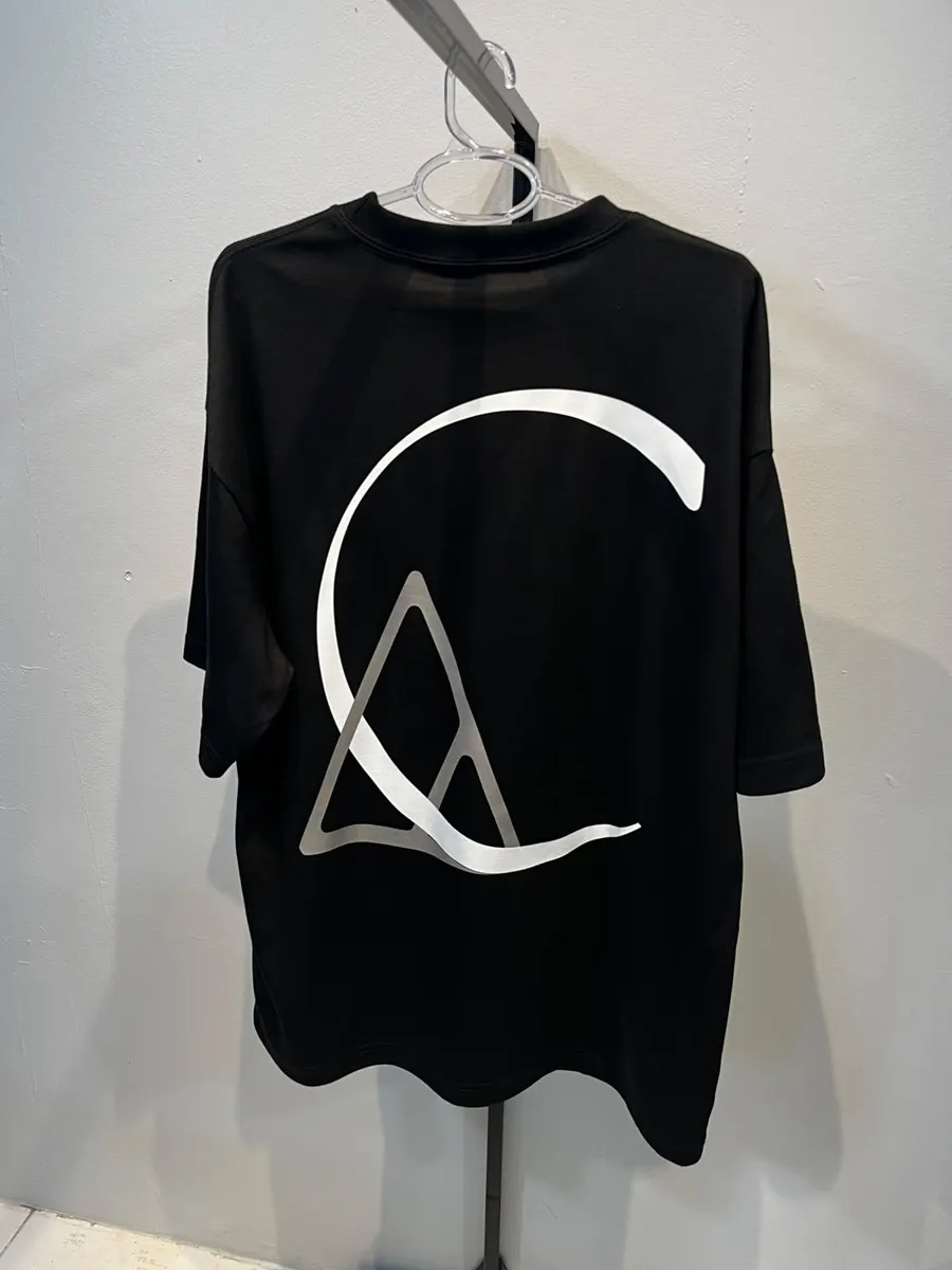 Camiseta oversized preta com monograma grande em branco e cinza nas costas